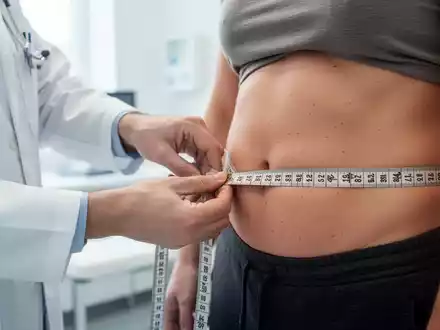 Ein Arzt misst in einer modernen medizinischen Praxis den Taillenumfang eines Patienten mit einem Maßband. - Foto: über boerse-global.de