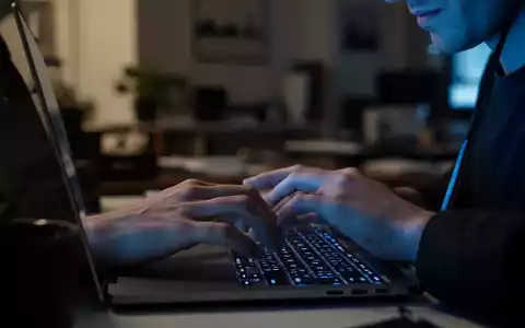 Nahaufnahme einer Person an einem Laptop in einem abgedunkelten Raum, die an ihre digitale Sicherheit denkt. - Foto: über boerse-global.de