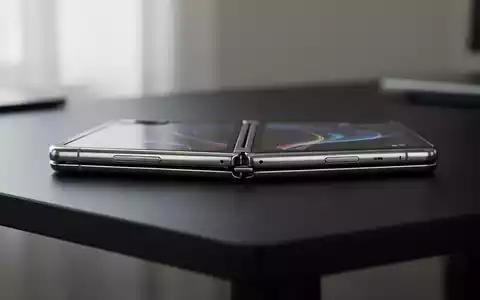 Ein faltbares Smartphone mit einem schlanken Metallgehäuse liegt auf einem schlichten, dunklen Tisch. - Foto: über boerse-global.de