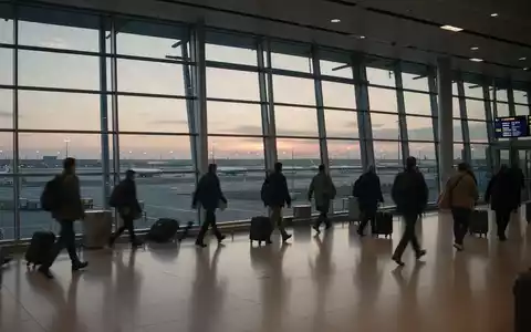 Geschäftiges Terminal eines internationalen Flughafens mit Reisenden vor großen Glasfronten bei Dämmerung. - Foto: über boerse-global.de