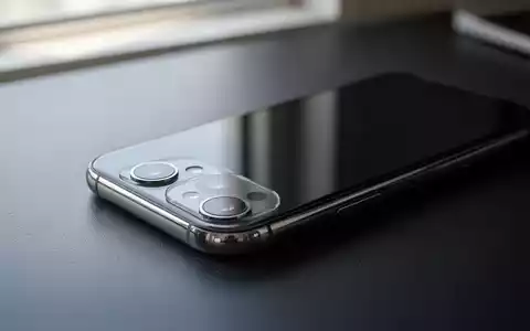 Ein modernes Smartphone liegt auf einem dunklen Schreibtisch, beleuchtet durch weiches, natürliches Licht. - Foto: über boerse-global.de