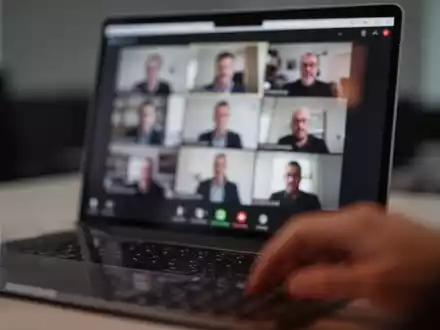 Nahaufnahme eines Laptops mit verschwommener Videokonferenz-Oberfläche in einem abgedunkelten Büro. - Foto: über boerse-global.de