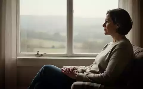 Eine entspannte Person blickt in einem hellen, ruhigen Raum aus einem Fenster und reflektiert in einem Moment der Stille. - Foto: über boerse-global.de