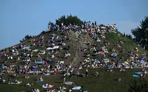 Erste Besucher bevölkern den Olympiaberg im MĂŒnchner Olympiapark, um von dort die partielle Sonnenfinsternis zu beobachten. - Foto: Felix Hörhager/dpa