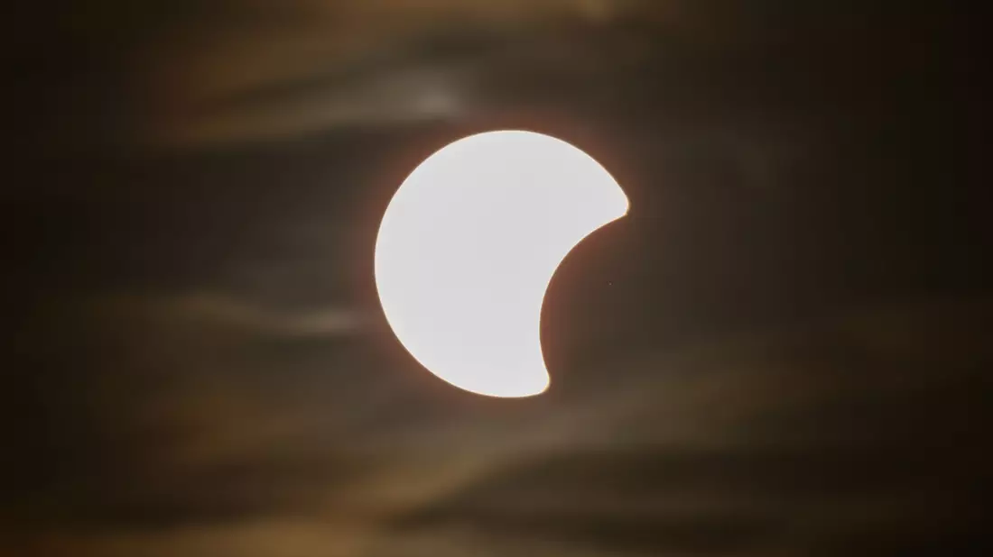 Der Beginn einer partiellen Sonnenfinsternis ist am Himmel über Dresden zu sehen. - Bild: Robert Michael/dpa
