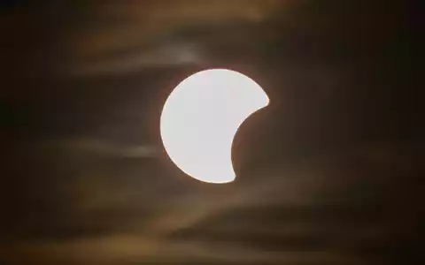 Der Beginn einer partiellen Sonnenfinsternis ist am Himmel über Dresden zu sehen. - Foto: Robert Michael/dpa