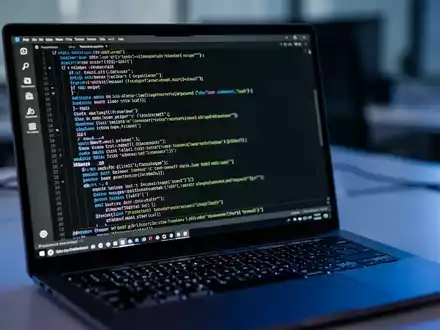 Ein Laptop-Bildschirm zeigt komplexen Programmiercode in einem dunklen Terminal-Fenster. - Foto: über boerse-global.de