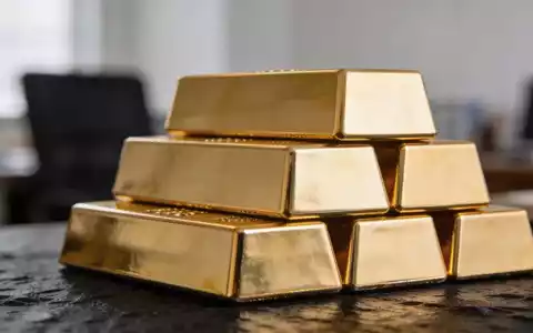 Goldbarren auf einem dunklen Untergrund gestapelt, beleuchtet durch weiches, natürliches Licht. - Foto: über boerse-global.de