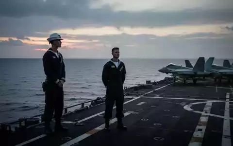 Ein einsamer US-Navy-Matrose steht bei Dämmerung auf dem Deck eines Flugzeugträgers und blickt auf den Ozean. - Foto: über boerse-global.de
