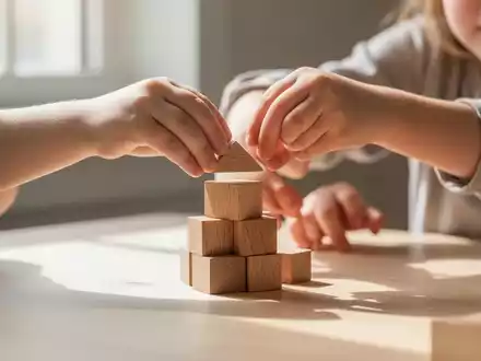 Hände eines Kindes beim Stapeln von Holzbausteinen auf einem Tisch, symbolisch für den Aufbau der Altersvorsorge. - Foto: über boerse-global.de