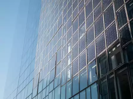 Moderne Glasfassade eines Hochhauses bei klarem Tageslicht, die den Himmel reflektiert. - Foto: über boerse-global.de