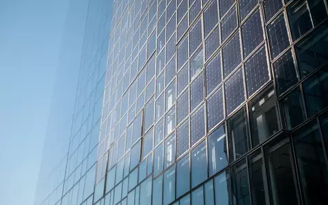 Moderne Glasfassade eines Hochhauses bei klarem Tageslicht, die den Himmel reflektiert. - Foto: über boerse-global.de