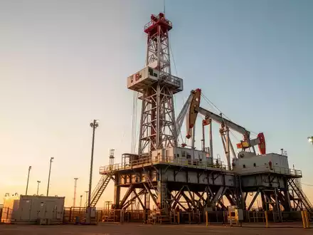 Ein moderner Bohrturm in einer Industrielandschaft während des Sonnenuntergangs. - Foto: über boerse-global.de