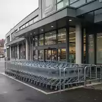 Eingangsbereich eines Supermarktes in einem städtischen Wohngebiet mit einer Reihe von Einkaufswagen. - Foto: über boerse-global.de