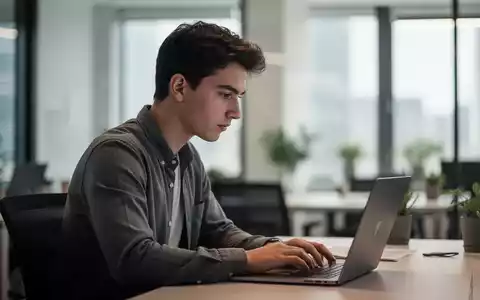Junger Erwachsener bei der Arbeit an einem Laptop in einem modernen Büro mit natürlichem Lichteinfall. - Foto: über boerse-global.de