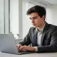 Ein junger Berufstätiger arbeitet konzentriert an einem Laptop in einem modernen, hellen Büro. - Foto: über boerse-global.de