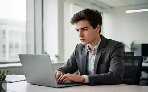 Ein junger Berufstätiger arbeitet konzentriert an einem Laptop in einem modernen, hellen Büro. - Foto: über boerse-global.de