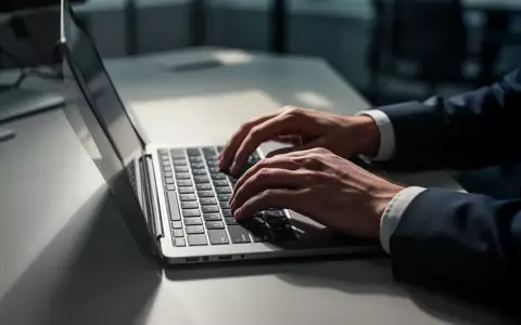 Hände an einer Laptop-Tastatur in einem modern beleuchteten Büro, Fokus auf digitale Sicherheit und Zahlungsverkehr. - Foto: über boerse-global.de