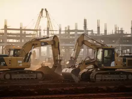 Baustelle mit schwerem Baugerät bei Sonnenuntergang als Symbol für Infrastrukturprojekte. - Foto: über boerse-global.de