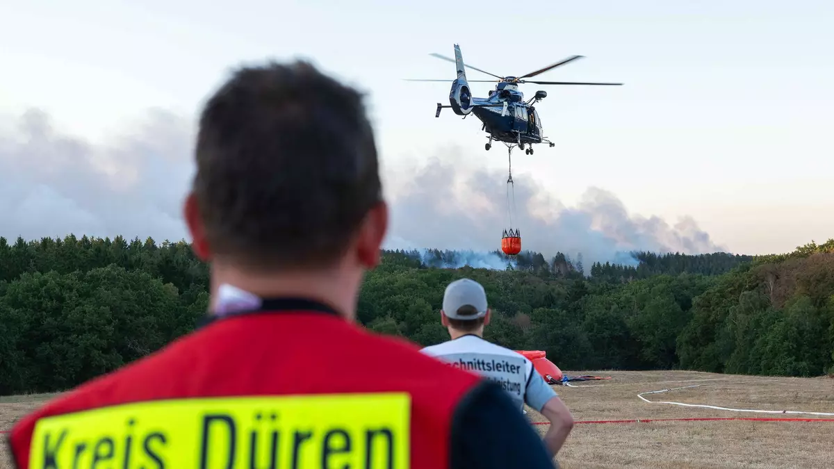 Ein Löschhubschrauber bekämpft am Donnerstagabend die Flammen des Waldbrandes Nahe Hürtgenwald. - Bild: Jan Ohmen/dpa
