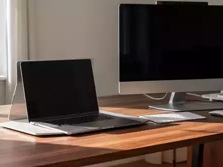 Ein moderner Schreibtisch mit einem Laptop und einem Desktop-PC in einer hellen, professionellen Arbeitsumgebung. - Foto: über boerse-global.de