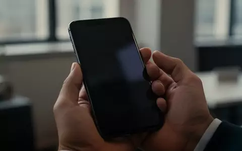 Ein Smartphone in einer Hand in einem Büro, das die Sicherheit von Mobilgeräten vor Spionagesoftware symbolisiert. - Foto: über boerse-global.de