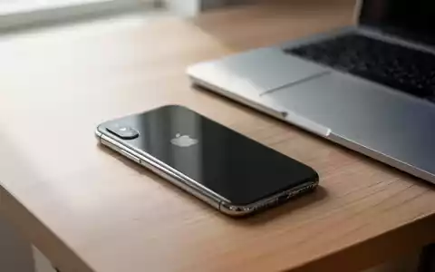 Ein iPhone X liegt auf einem minimalistischen Schreibtisch neben einem geschlossenen Laptop. - Foto: über boerse-global.de