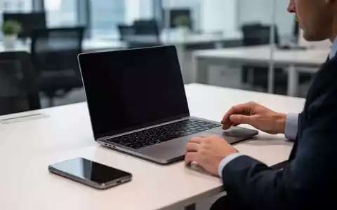Eine Person sitzt an einem modernen Schreibtisch mit Laptop und Smartphone in einer professionellen Büroumgebung. - Foto: über boerse-global.de