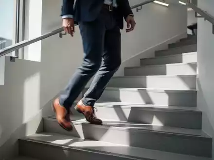 Eine Person geht in einem hellen Treppenhaus die Stufen hinauf, um sich sportlich zu betätigen. - Foto: über boerse-global.de