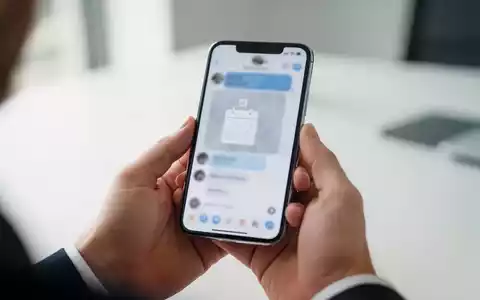 Person hält ein Smartphone in einem modernen Büro, während der Fokus auf der Interaktion mit einer Messenger-App liegt. - Foto: über boerse-global.de