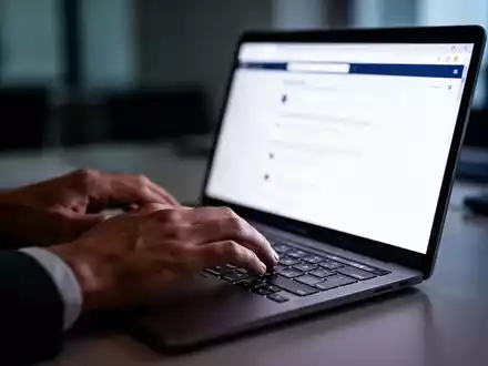 Hände beim Tippen auf einer Laptop-Tastatur in einem Büro, während auf dem Bildschirm ein Browser-Fenster zu sehen ist. - Foto: über boerse-global.de