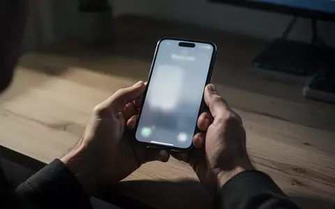 Nahaufnahme einer Person, die in einem dunklen Büro besorgt auf ihr Smartphone schaut, während sie Online-Banking nutzt. - Foto: über boerse-global.de