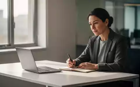 Eine konzentrierte Person arbeitet ruhig an einem minimalistischen Schreibtisch mit Laptop und Notizbuch in einem hellen Büro. - Foto: über boerse-global.de