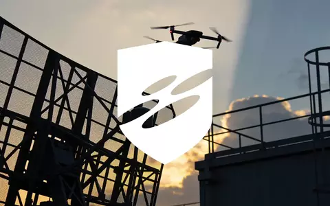 Eine moderne Überwachungsdrohne vor einem atmosphärischen Dämmerungshimmel über einer Industrielandschaft. - Foto: über boerse-global.de