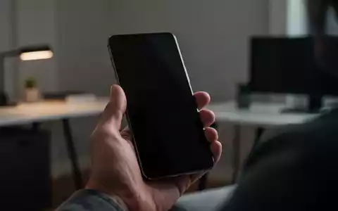 Eine Person hält ein modernes Smartphone in einem Büro, wobei der Fokus auf der Sicherheitstechnologie des Geräts liegt. - Foto: über boerse-global.de