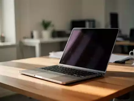 Ein moderner, aufgeräumter Arbeitsplatz mit einem aufgeklappten Laptop auf einem Holztisch bei natürlichem Tageslicht. - Foto: über boerse-global.de