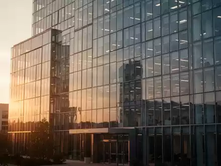 Ein modernes Bürogebäude bei Sonnenuntergang als Symbol für Finanztransaktionen. - Foto: über boerse-global.de