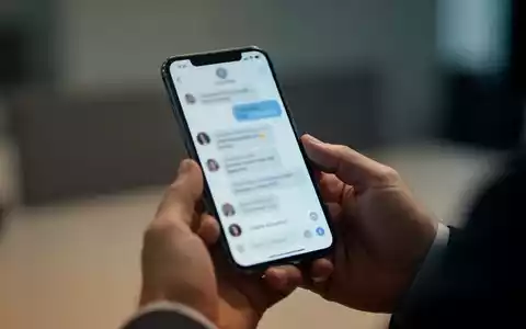 Nahaufnahme einer Person, die ein Smartphone in der Hand hĂ€lt, wĂ€hrend sie eine Chat-App in einer BĂŒroumgebung nutzt. - Foto: ĂŒber boerse-global.de