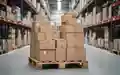 Ein Stapel Pappkartons auf einer Holzpalette in einem modernen Lagerhaus, symbolisch für Verpackungslogistik. - Foto: über boerse-global.de