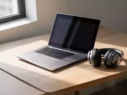 Ein moderner, aufgeräumter Arbeitsplatz mit einem Laptop und Kopfhörern in sanftem Tageslicht. - Foto: über boerse-global.de