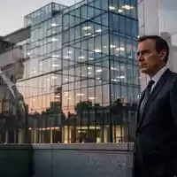 Ein Diplomat in einem Anzug vor einem modernen Bürogebäude in Brüssel bei Dämmerung. - Foto: über boerse-global.de