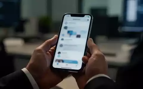 Nahaufnahme einer Hand, die ein Smartphone in einem Büro hält, während sie eine digitale Sicherheitswarnung prüft. - Foto: über boerse-global.de
