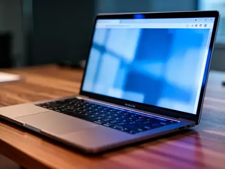 Ein moderner Arbeitsplatz mit einem Laptop in einem dezent beleuchteten Büro, Fokus auf die Tastatur und den Bildschirmrand. - Foto: über boerse-global.de