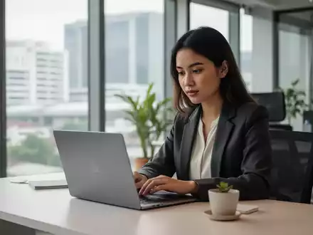 Eine junge Frau arbeitet in einem modernen Büro in Manila an ihrem Laptop, umgeben von einer hellen, professionellen Arbeitsumgebung. - Foto: über boerse-global.de