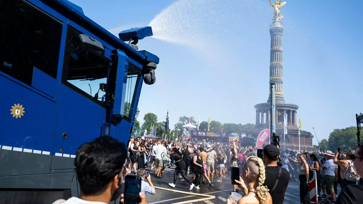 Ein Wasserwerfer der Polizei verschafft den Ravern etwas Abkühlung.   - Bild: Christophe Gateau/dpa