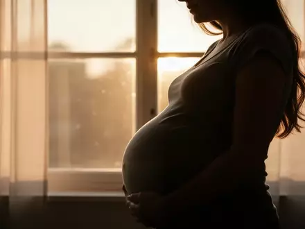 Nahaufnahme der Silhouette einer schwangeren Frau vor einem sonnendurchfluteten Fenster. - Foto: über boerse-global.de