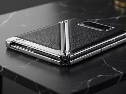 Ein luxuriöses, teilweise zusammengeklapptes Smartphone aus Platin und Leder auf einem dunklen Marmortisch. - Foto: über boerse-global.de