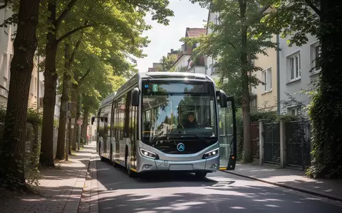 Ein moderner elektrischer Midibus fährt durch eine schmale, von Bäumen gesäumte Straße in einem Münchner Stadtviertel. - Foto: über boerse-global.de