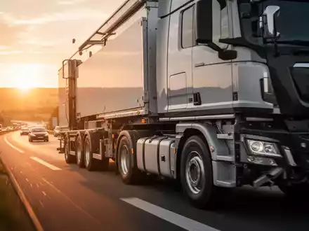 Ein schwerer Lastkraftwagen fährt bei Sonnenuntergang auf einer Autobahn. - Foto: über boerse-global.de