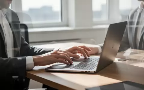 Eine Person sitzt an einem modernen Schreibtisch vor einem Laptop in einem hellen, professionell eingerichteten Büro. - Foto: über boerse-global.de